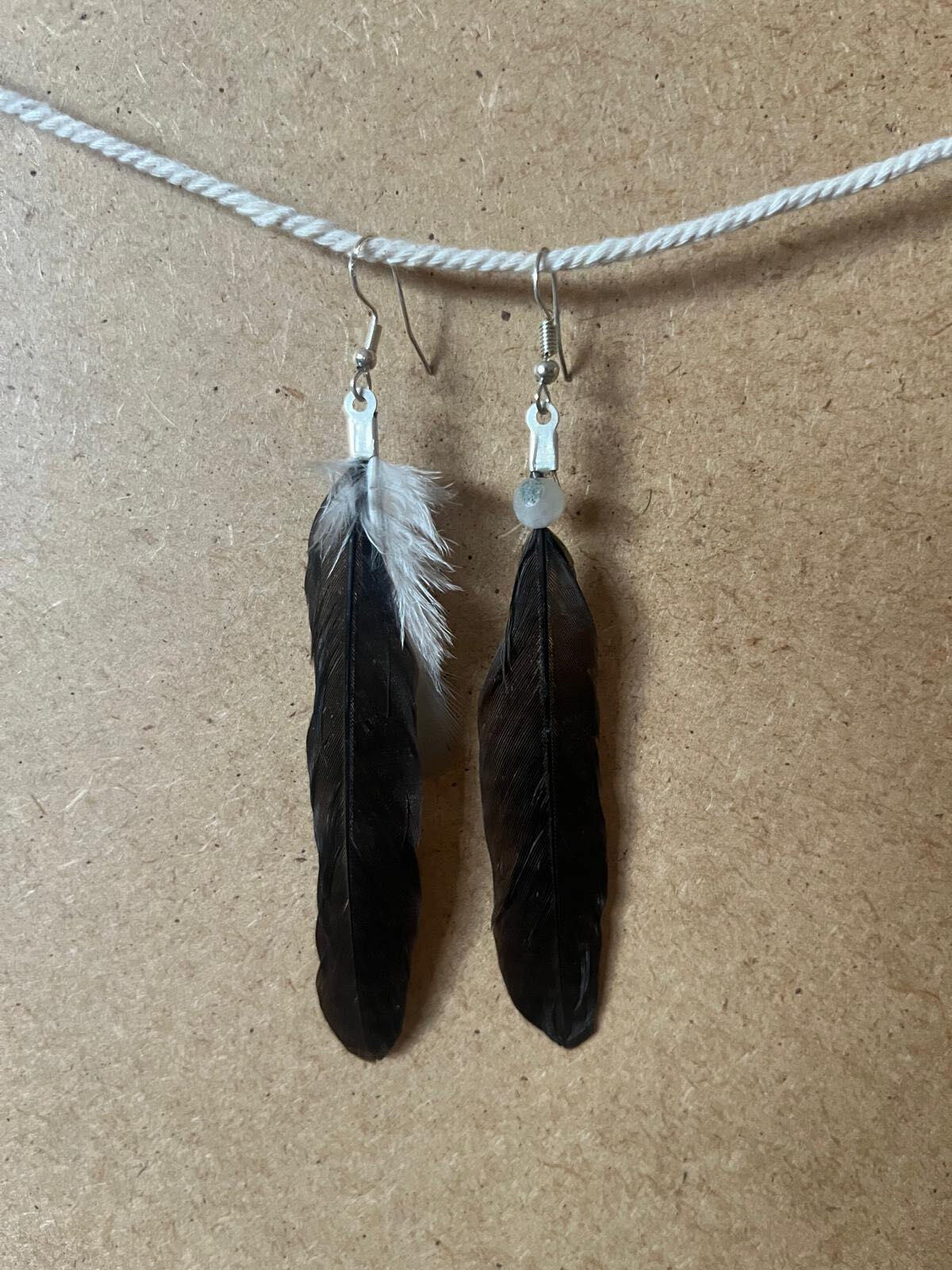 Handcrafted Negro Esencial earrings with black feathers and a light detail in a sober composition