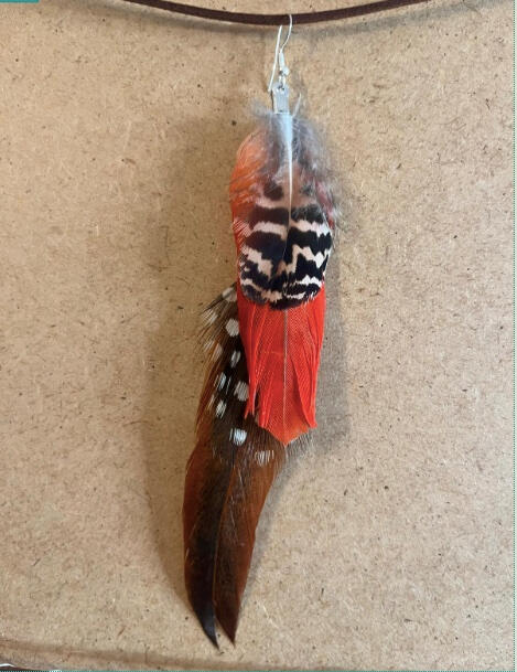 Pendiente artesanal Latido Rojo con plumas rojas intensas, moteadas y tonos oscuros en composición vertical