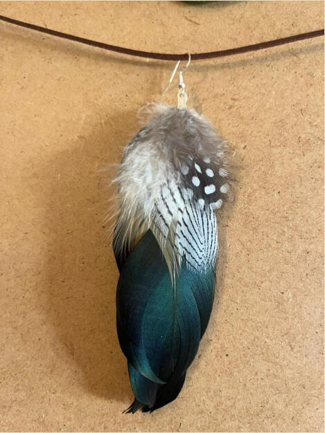 Pendiente artesanal Verde Silente con plumas verdes profundas, grises y moteadas en composición vertical natural