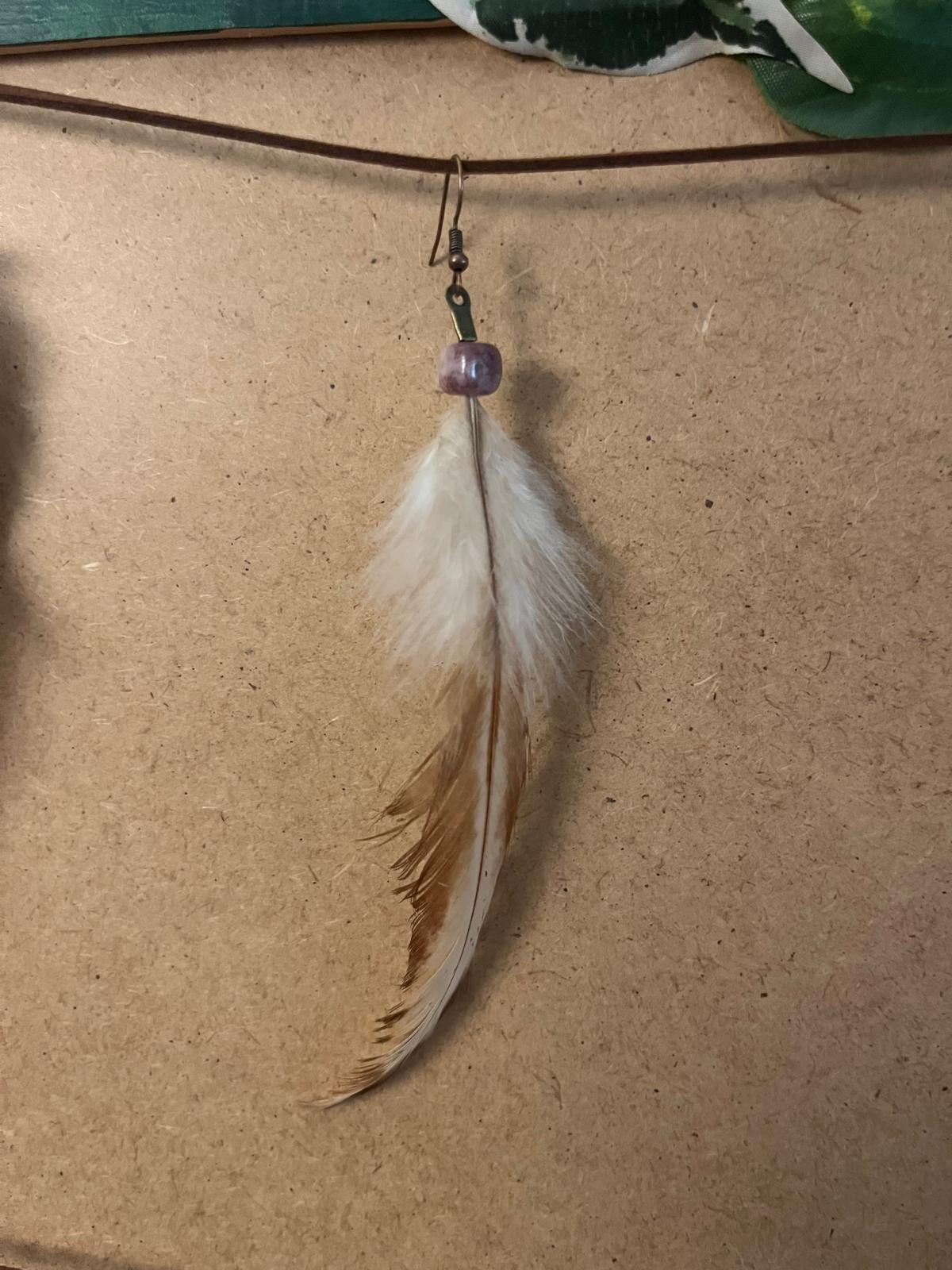 Pendiente artesanal Alba Serena con pluma clara y tonos suaves en caída vertical natural